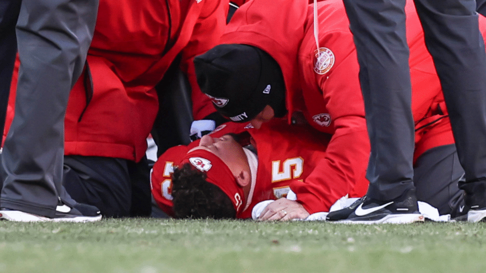 Kansas City Chiefs training staff talk with quarterback Patrick Mahomes (15) as he lies on the ground after injuring his knee in the fourth quarter of an NFL game between the Los Angeles Chargers and Kansas City Chiefs on December 14, 2025 at GEHA Field at Arrowhead Stadium in Kansas City, MO.