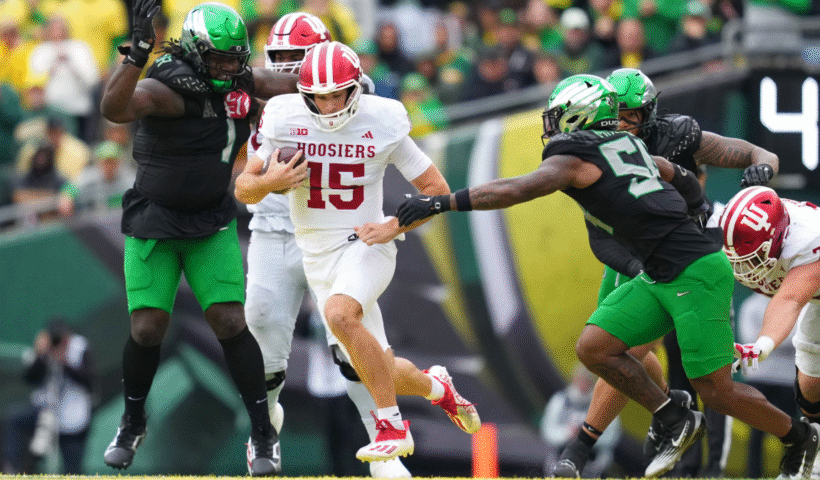 Fernando Mendoza #15 of the Indiana Hoosiers attempts to avoid a tackle by Jerry Mixon #54 of the Oregon Ducks during the second half at Autzen Stadium on October 11, 2025 in Eugene, Oregon.