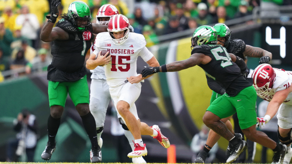 Fernando Mendoza #15 of the Indiana Hoosiers attempts to avoid a tackle by Jerry Mixon #54 of the Oregon Ducks during the second half at Autzen Stadium on October 11, 2025 in Eugene, Oregon.