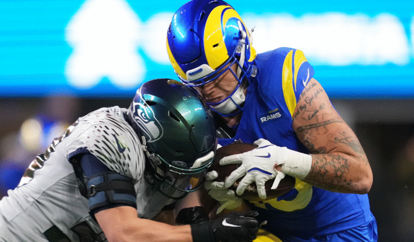 Josaiah Stewart #10 of the Los Angeles Rams is hit by Ty Okada #39 of the Seattle Seahawks during the fourth quarter at Lumen Field on December 18, 2025 in Seattle, Washington.