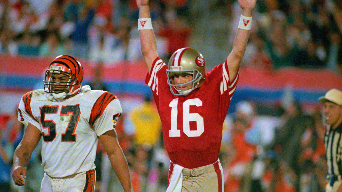49ers quarterback Joe Montana raises his arm in celebration after throwing a touchdown pass to Jerry Rice in the fourth quarter. Bengal Sam Kennedy looks on.